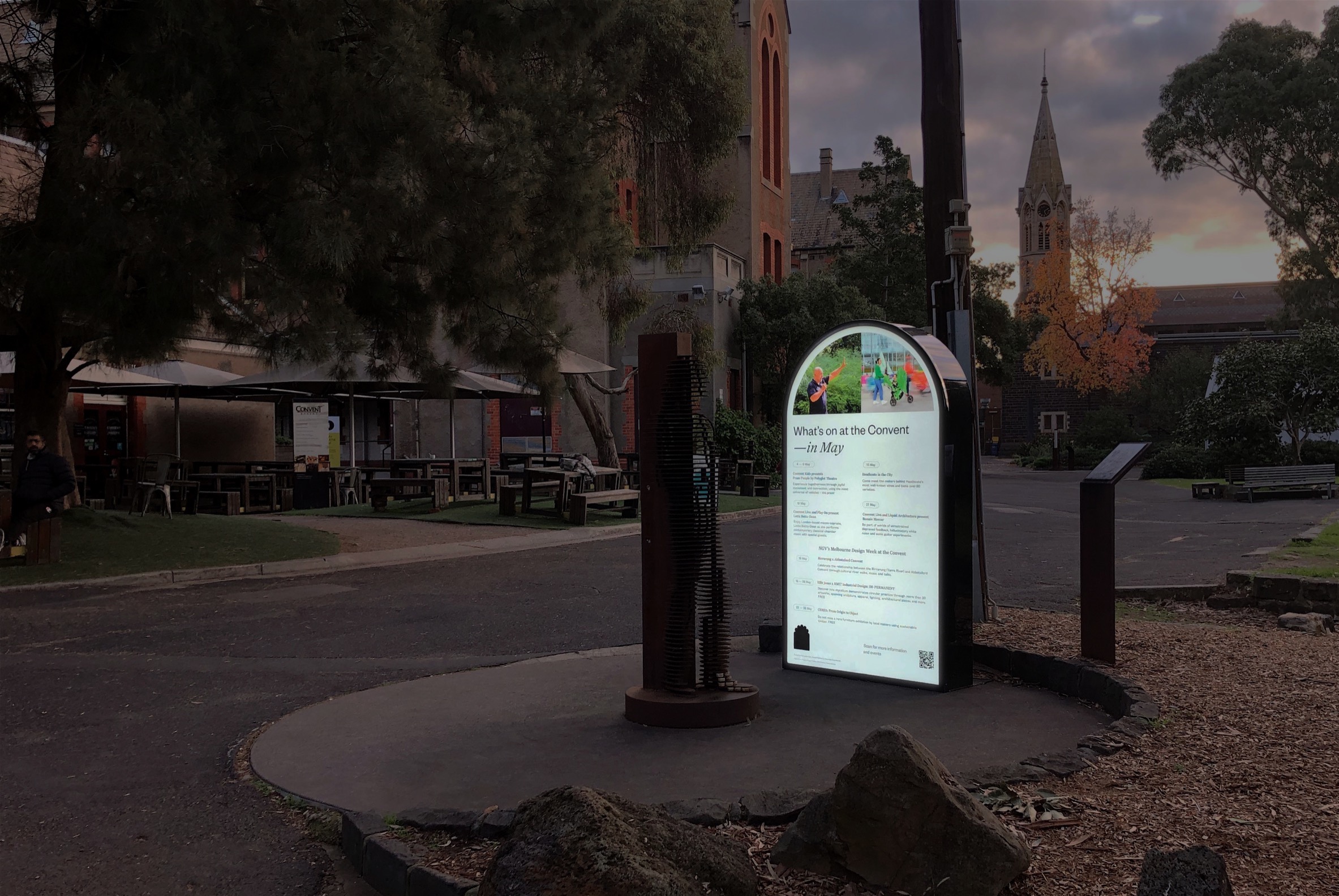 An arch-shaped lightbox sign, pictured at dusk on the Abbotsford Convent grounds.